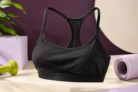 Brassière de sport noire à bretelles fines et dos nageur, présentée seule sur un fond de studio lumineux.