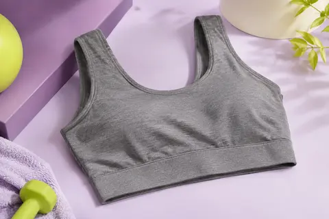 Brassière de sport Fila grise à couverture totale, posée sur un fond de studio prune et ivoire.