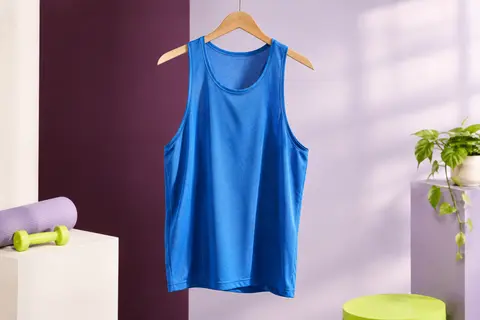 Débardeur de sport bleu à coupe ample et emmanchures larges, présenté seul dans un studio lumineux.