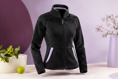 Veste polaire noire pour femme avec col montant et poches kangourou, présentée sur fond prune et ivoire.
