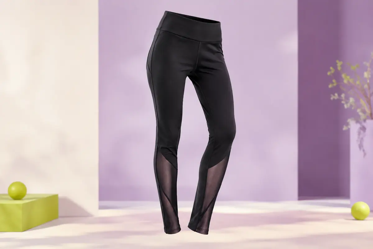Legging de sport noir et blanc présenté en studio, avec ceinture élastique large et panneaux en mesh aux mollets.