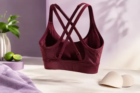 Brassière de sport rouge vineux à doubles bretelles croisées, avec ses coussinets amovibles posés à côté