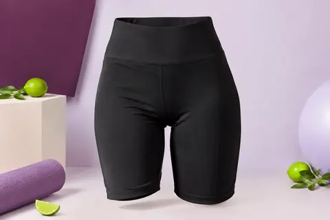 Short cycliste noir à taille haute, posé seul sur un fond de studio prune et lilas pâle.